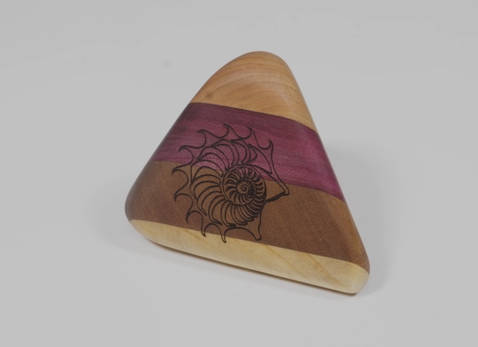 Handcrafted multicolored wooden triangle block with nautilus shell engraving and purple staining